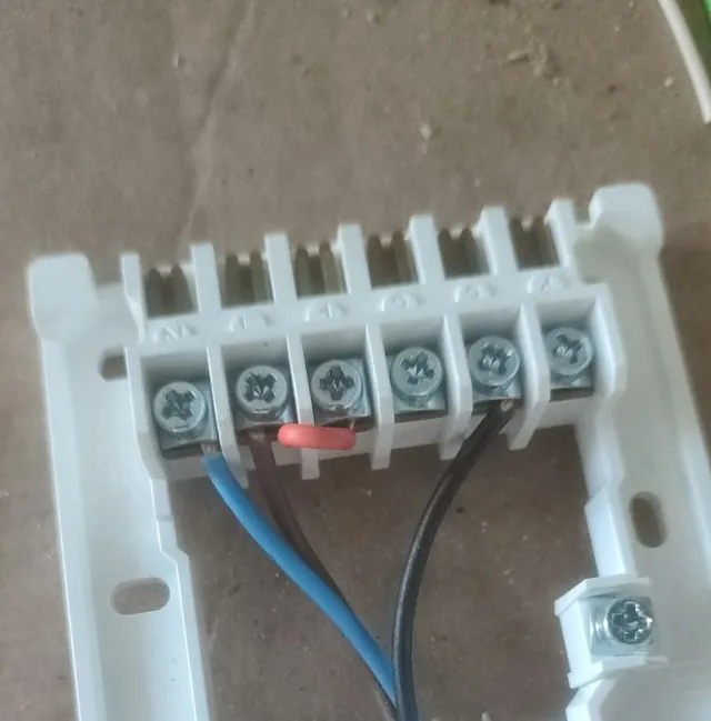 The wiring plate of a heating control with blue, brown and black wires in its terminals